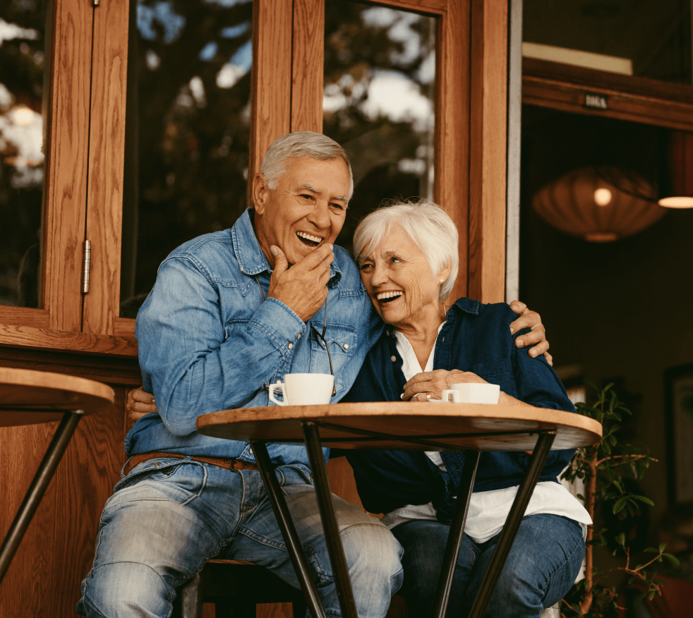 Elderly couple laughing while drinking coffee